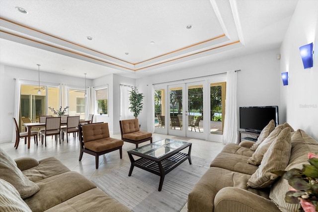 tiled living room with a tray ceiling, ceiling fan, and french doors