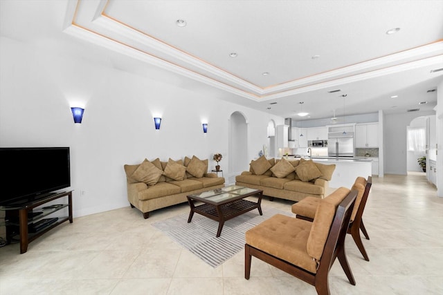 living room featuring a raised ceiling, light tile patterned flooring, and ornamental molding