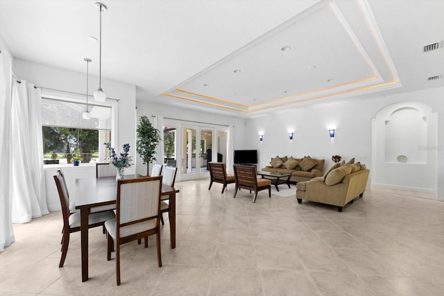 dining area with a healthy amount of sunlight, a raised ceiling, and french doors