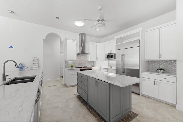 kitchen with white cabinetry, wall chimney exhaust hood, decorative light fixtures, and appliances with stainless steel finishes