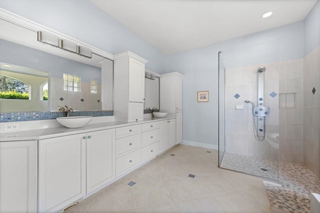 bathroom featuring a tile shower, tile patterned flooring, and vanity