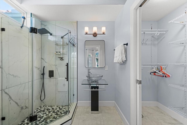 bathroom with tile patterned floors, a shower with door, and sink