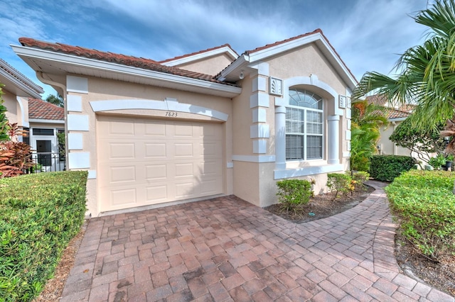 mediterranean / spanish house featuring decorative driveway, an attached garage, and stucco siding