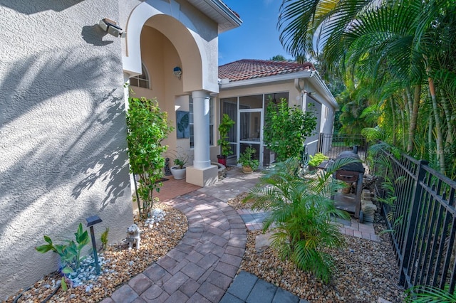 view of exterior entry featuring a patio area, a tile roof, fence, and stucco siding