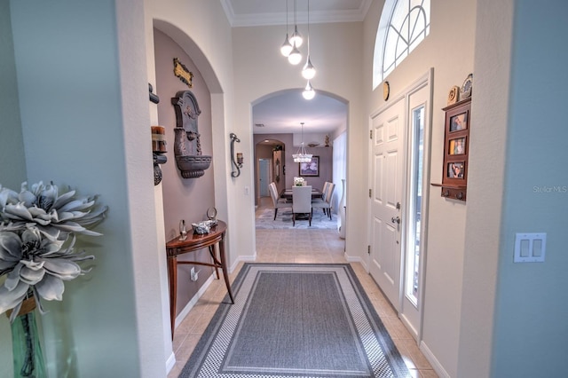 foyer with light tile patterned floors, ornamental molding, and arched walkways