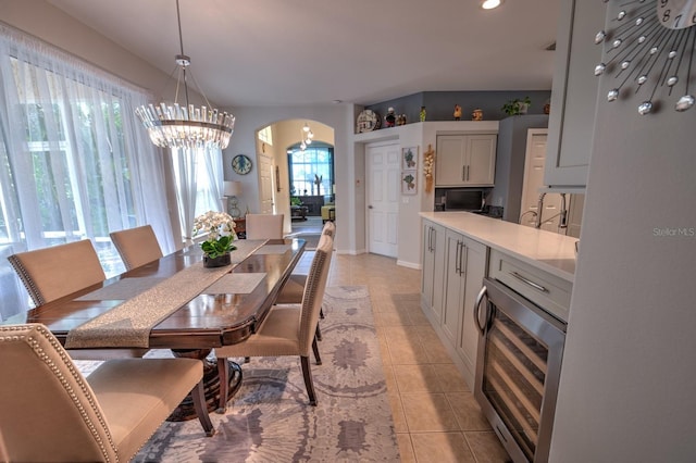 dining area with arched walkways, light tile patterned floors, recessed lighting, beverage cooler, and baseboards