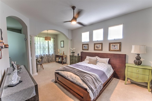 carpeted bedroom with a ceiling fan, arched walkways, and ornate columns