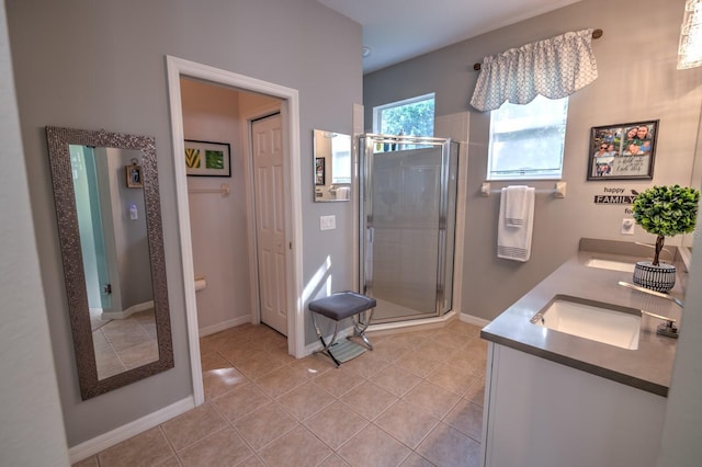 bathroom with double vanity, a shower stall, baseboards, and tile patterned flooring