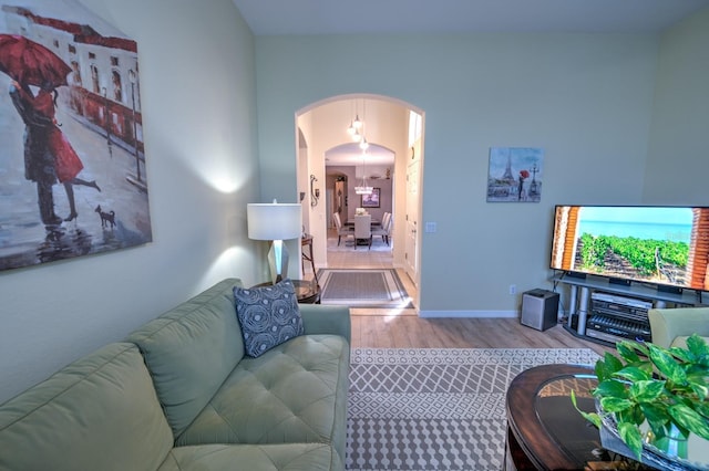 living area featuring arched walkways, baseboards, and wood finished floors