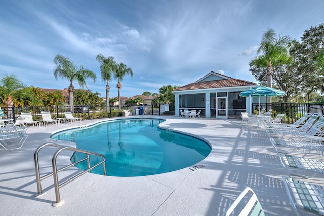 community pool with a sunroom, a patio area, and fence