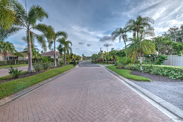 view of street featuring street lights, a gated entry, and curbs