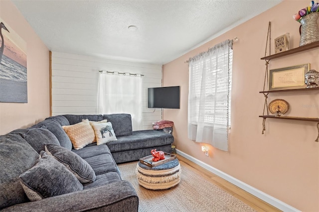 living room featuring a textured ceiling, light hardwood / wood-style flooring, and wooden walls