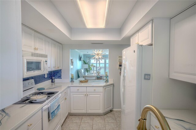 kitchen featuring light tile patterned floors, white cabinets, white appliances, and a tray ceiling