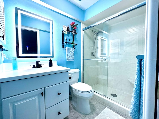 bathroom featuring a shower with shower door, toilet, vanity, and tile patterned floors