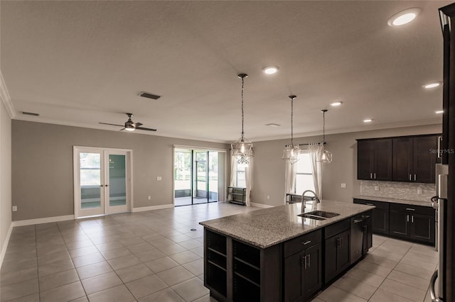 kitchen featuring a kitchen island with sink, sink, light stone counters, and ornamental molding