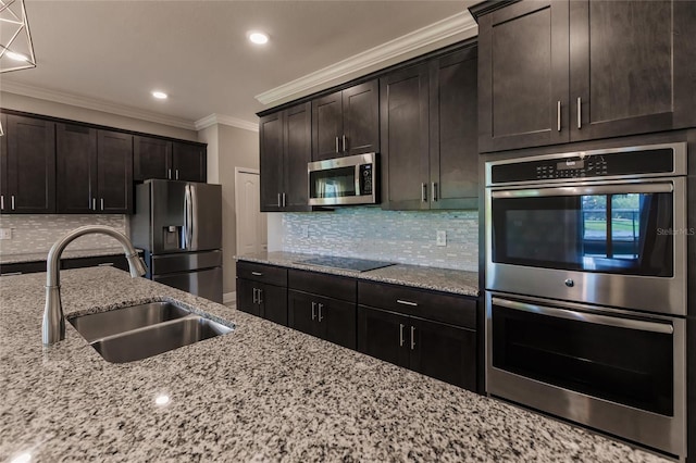 kitchen with sink, appliances with stainless steel finishes, dark brown cabinets, light stone countertops, and ornamental molding