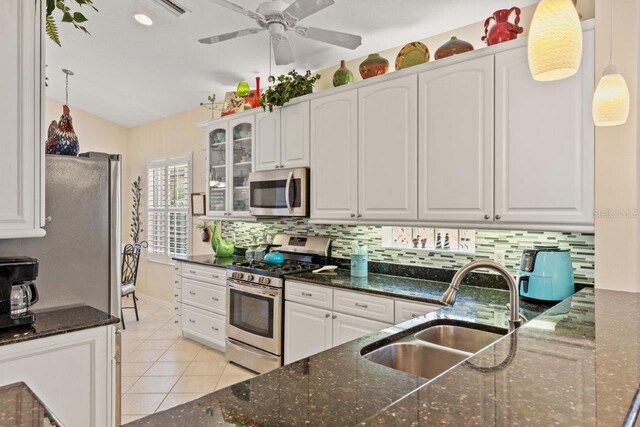 kitchen featuring backsplash, sink, stainless steel appliances, and dark stone countertops