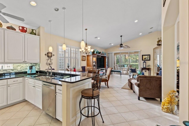 kitchen featuring ceiling fan with notable chandelier, vaulted ceiling, dishwasher, kitchen peninsula, and light tile patterned flooring