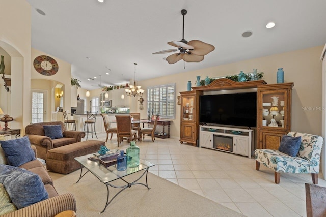 living room with ceiling fan with notable chandelier and light tile patterned floors