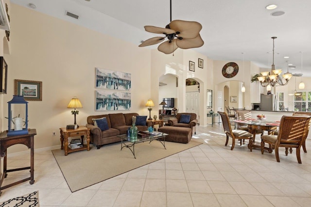 living room featuring ceiling fan with notable chandelier, a high ceiling, and light tile patterned flooring