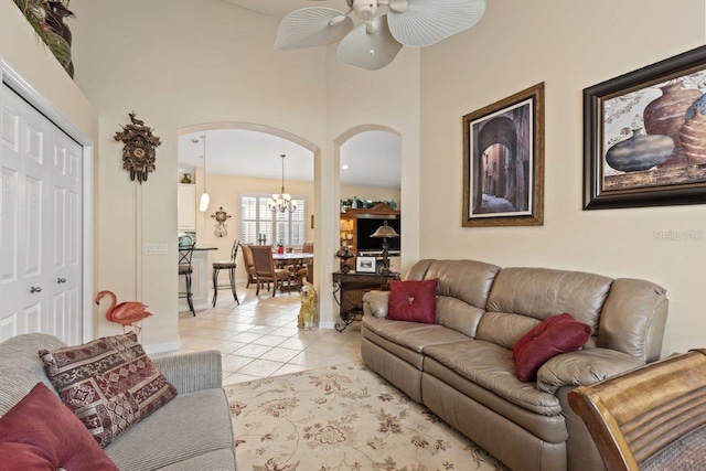 living room with light tile patterned flooring and ceiling fan with notable chandelier