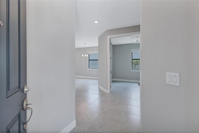 hallway featuring light tile patterned floors and a chandelier