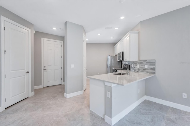 kitchen with white cabinetry, tasteful backsplash, stainless steel appliances, kitchen peninsula, and sink