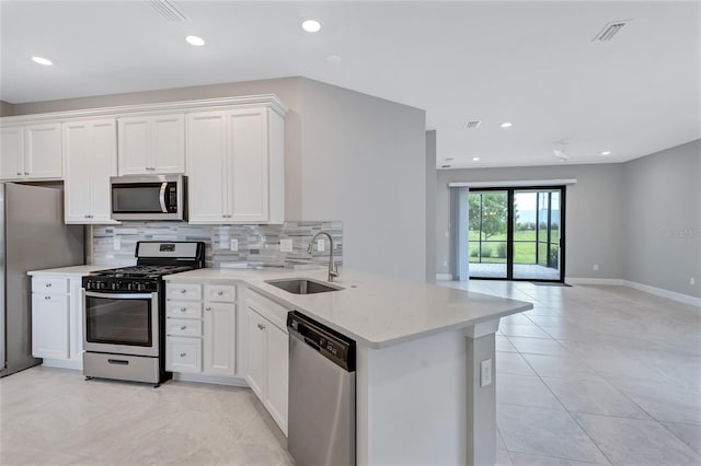 kitchen with appliances with stainless steel finishes, white cabinetry, kitchen peninsula, and sink