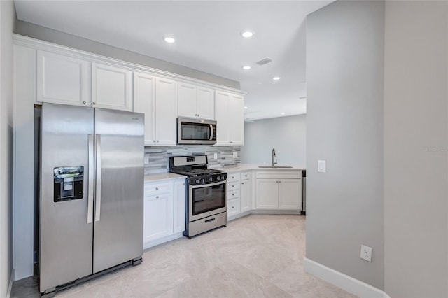 kitchen featuring appliances with stainless steel finishes, backsplash, white cabinetry, and sink