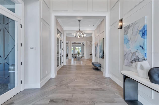 hallway with ornamental molding and a notable chandelier