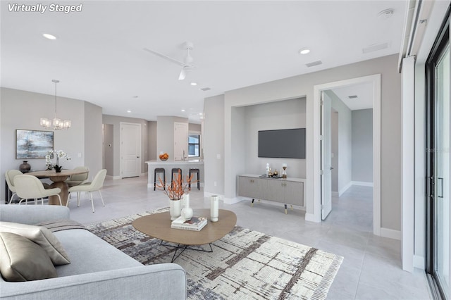 tiled living room with ceiling fan with notable chandelier