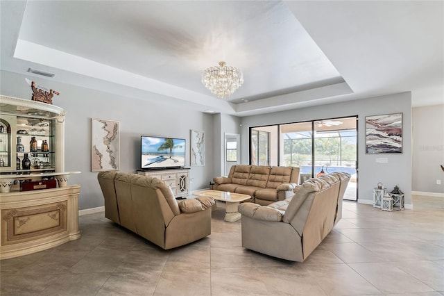 living room with a raised ceiling, light tile patterned floors, and a chandelier