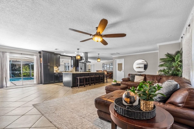 living room with ceiling fan, a textured ceiling, crown molding, and light tile patterned floors