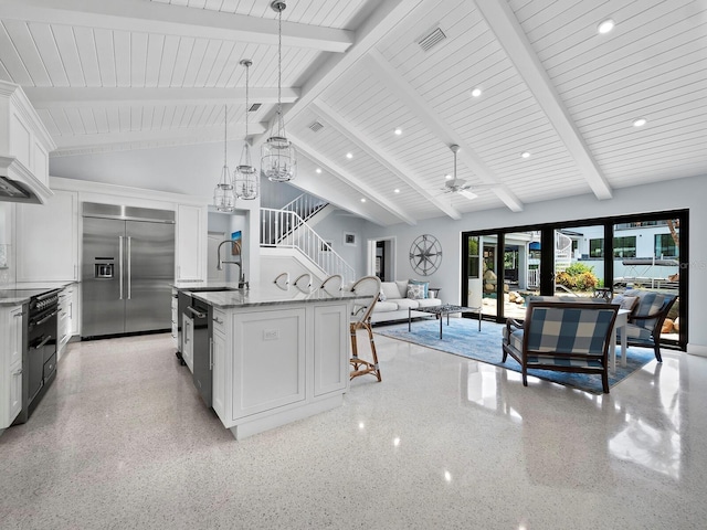 kitchen featuring white cabinets, built in refrigerator, an island with sink, high vaulted ceiling, and beam ceiling