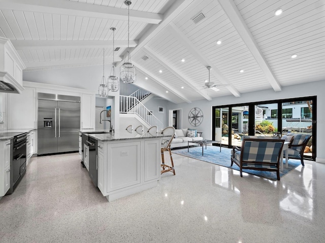 1400 Quail Dr, Sarasota, FL 34231 - kitchen featuring light speckled floor, built in refrigerator, a center island with sink, and white cabinetry