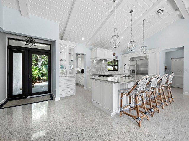 kitchen featuring hanging light fixtures, stainless steel appliances, white cabinetry, beam ceiling, and tasteful backsplash