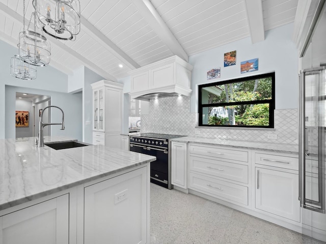1400 Quail Dr, Sarasota, FL 34231 - kitchen featuring light speckled floor, range with two ovens, a sink, white cabinetry, and light stone countertops