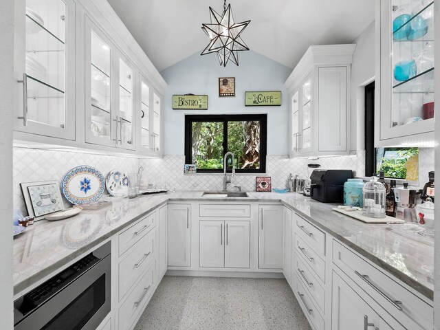 kitchen with white cabinetry, backsplash, and lofted ceiling