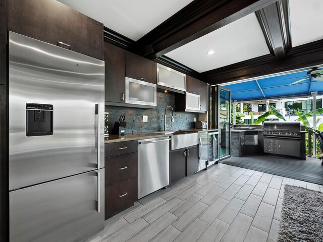 kitchen with tasteful backsplash, dark brown cabinets, sink, ceiling fan, and appliances with stainless steel finishes