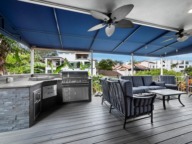 wooden terrace featuring an outdoor living space, exterior kitchen, ceiling fan, and grilling area