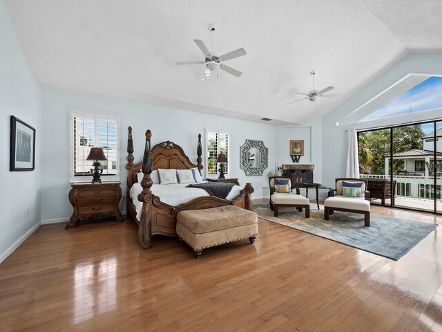 bedroom with vaulted ceiling, hardwood / wood-style floors, ceiling fan, and multiple windows