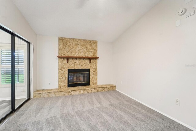 unfurnished living room with lofted ceiling, carpet, and a stone fireplace