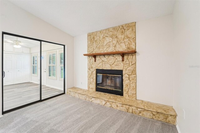 unfurnished living room featuring vaulted ceiling, wood-type flooring, ceiling fan, and a stone fireplace