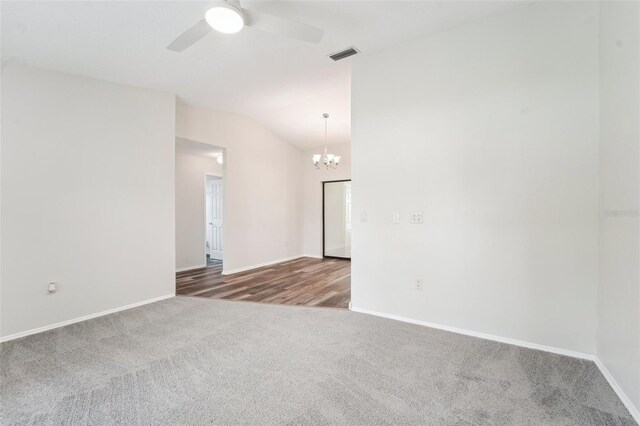 empty room featuring lofted ceiling, ceiling fan with notable chandelier, and carpet floors