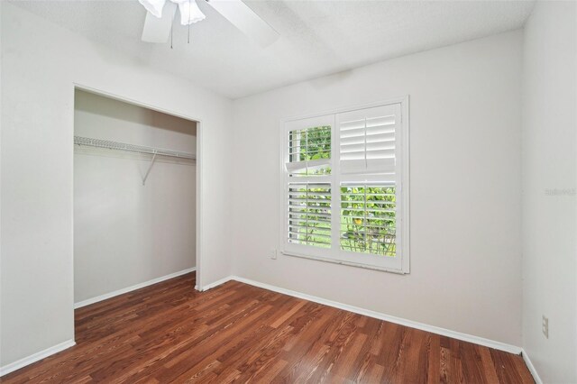 unfurnished bedroom with dark wood-type flooring, a closet, ceiling fan, and a textured ceiling