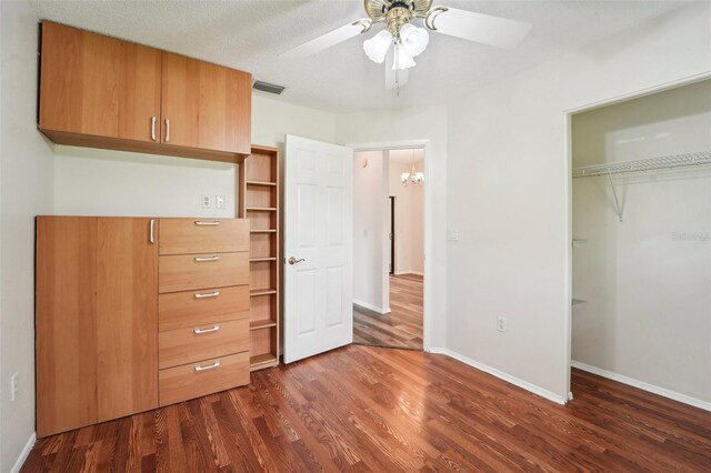 unfurnished bedroom with a textured ceiling, dark hardwood / wood-style flooring, ceiling fan, and a closet