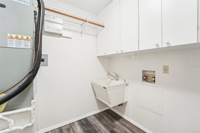 clothes washing area with dark wood-type flooring, hookup for a washing machine, cabinets, and sink