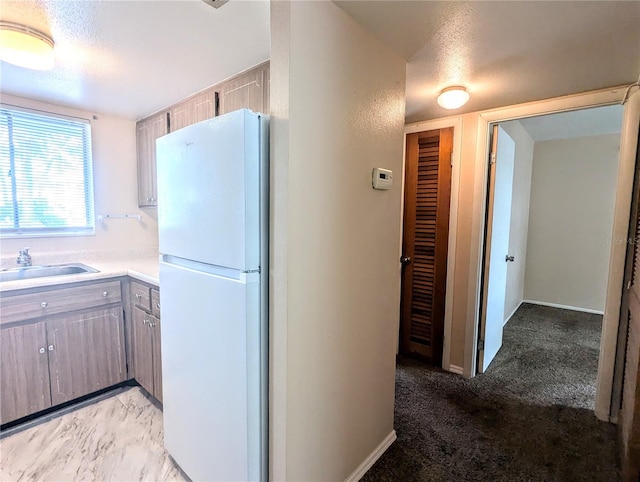 kitchen with sink, white refrigerator, and light carpet