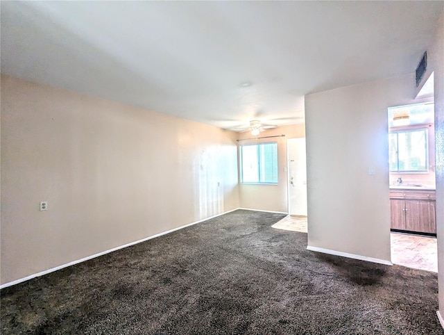 spare room featuring carpet, sink, and ceiling fan