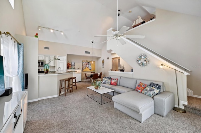 carpeted living room featuring high vaulted ceiling, ceiling fan, and track lighting